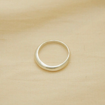 thin yet sturdy silver ring, bulbous and smooth, sitting on fabric