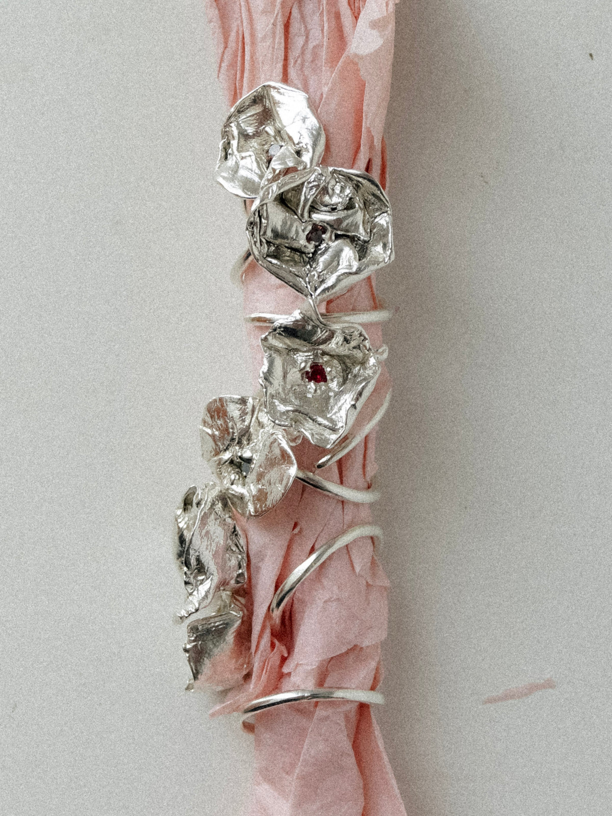 Bloom sterling silver flower rings with red CZ centres arranged on pink tissue