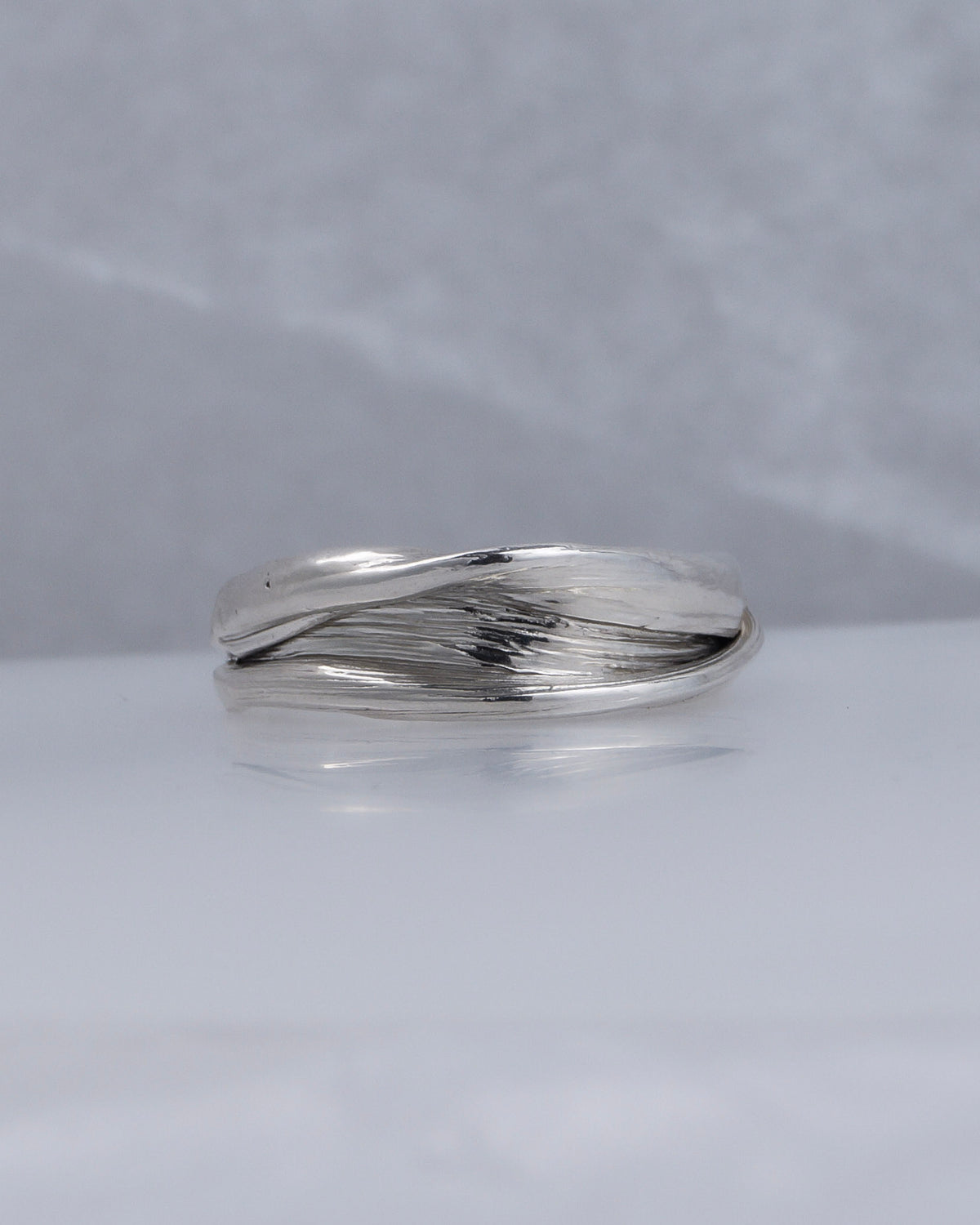 Front view of the Fold 005 sterling silver ring on a pale surface