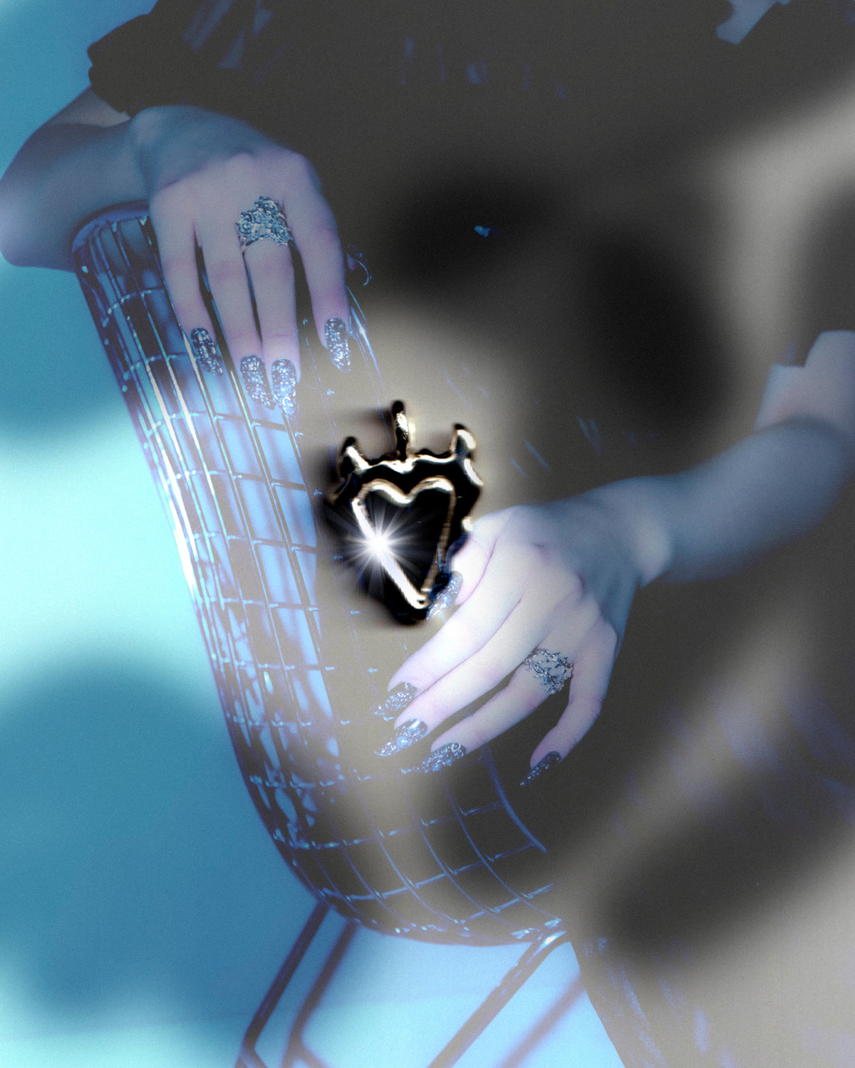 Baddie sculptural heart pendant held in an editorial blue-lit portrait
