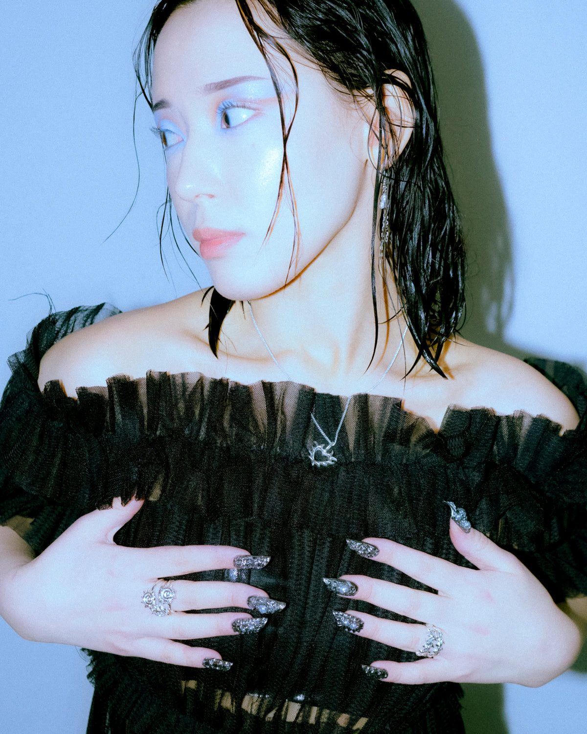 heart shaped silver pendant on silver chain on asian girl wearing black dress, silver rings and molten long fake nails
