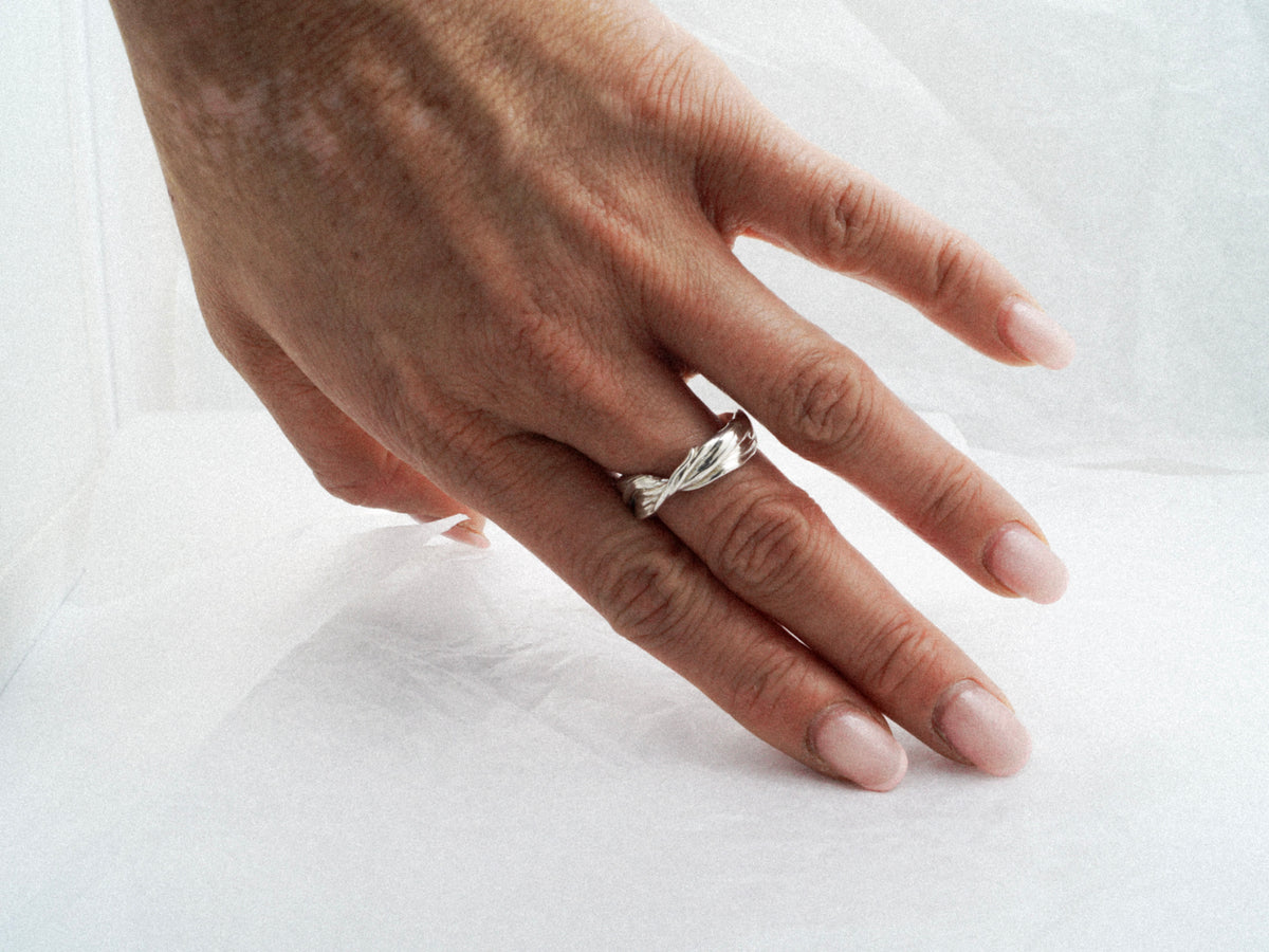 Hand wearing the Fold 006 crossed-fold sterling silver ring