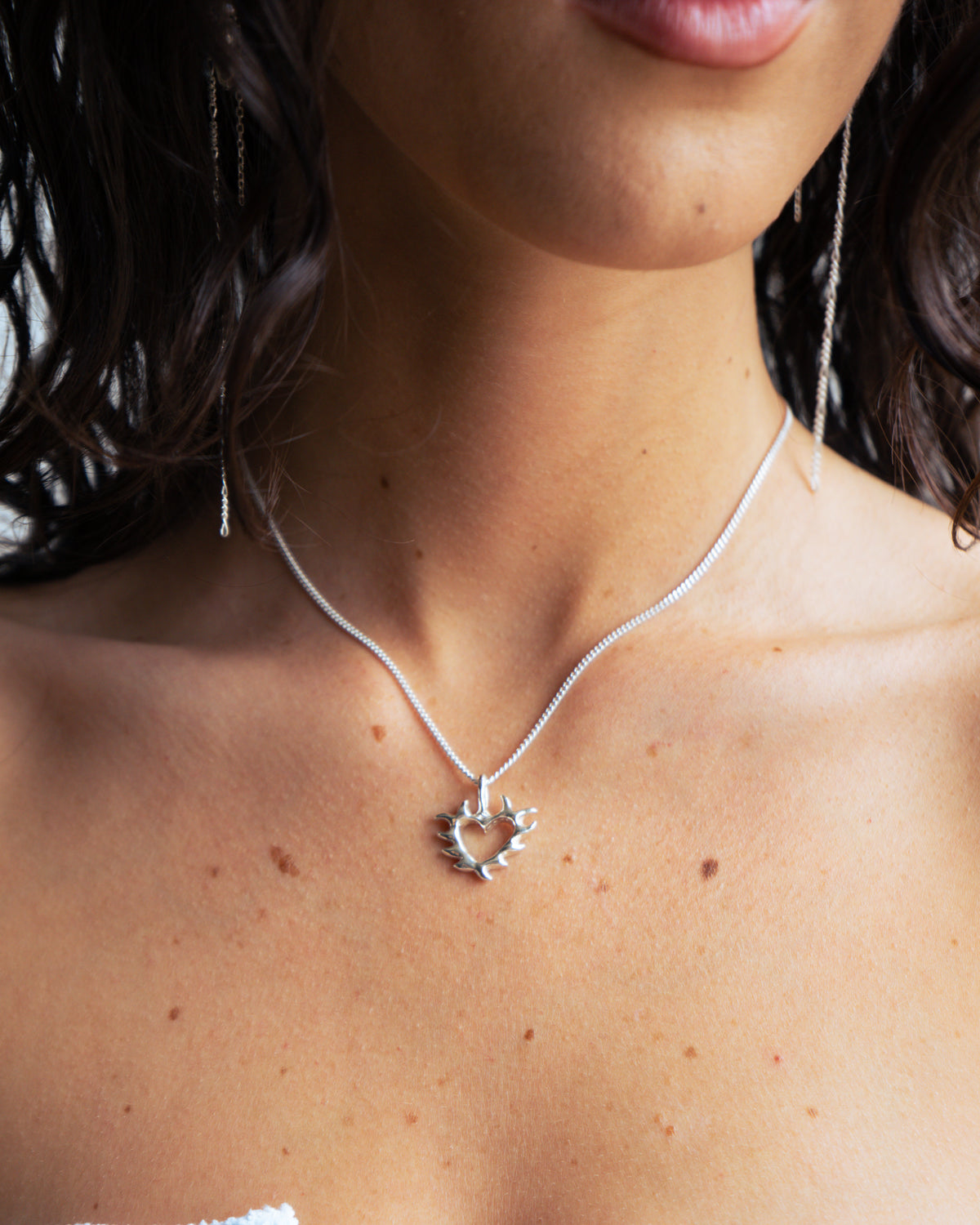 Close-up of a necklace with a heart pendant on a person's neck.
