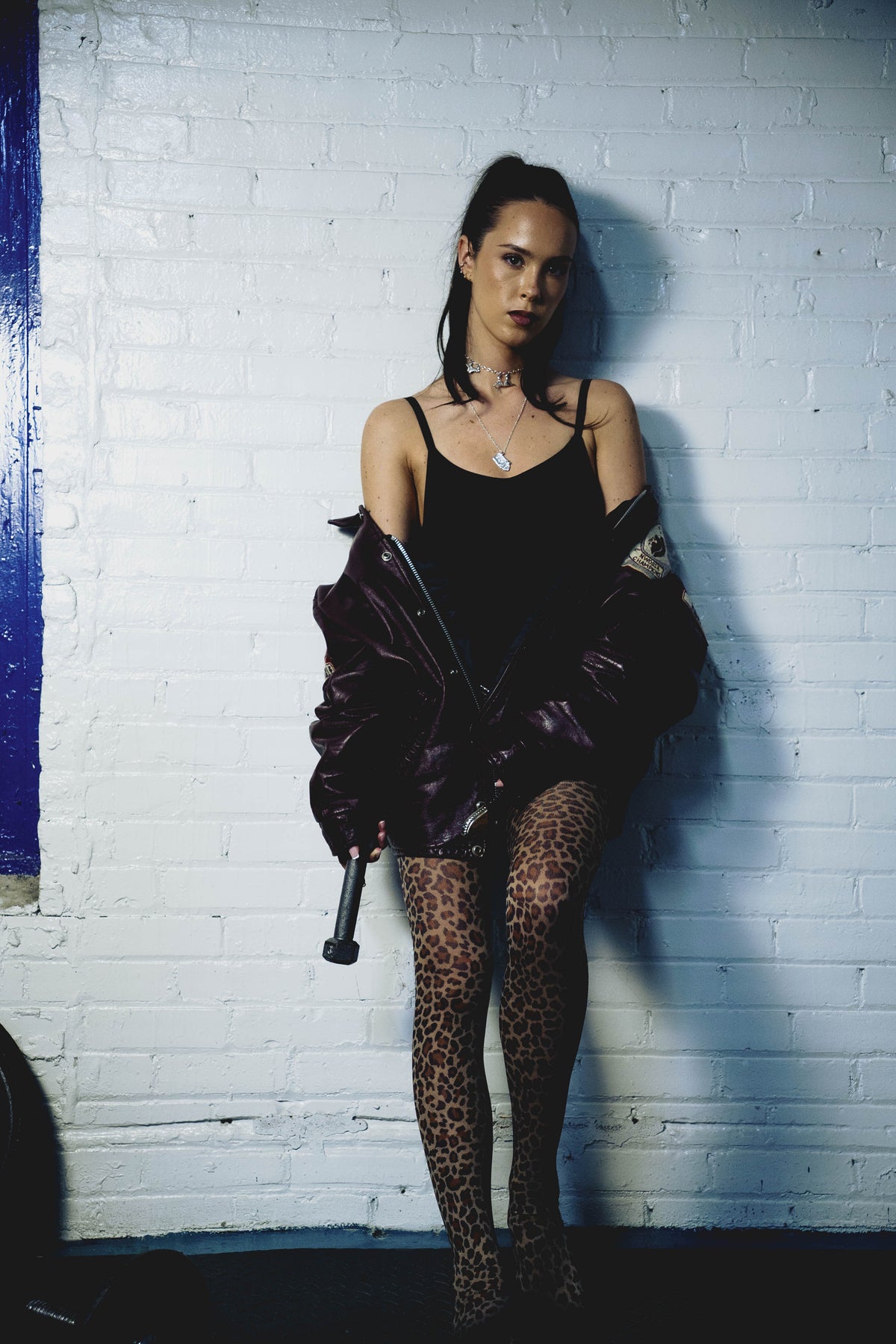Model wearing the Big Baby sterling silver pendant necklace against a white brick wall