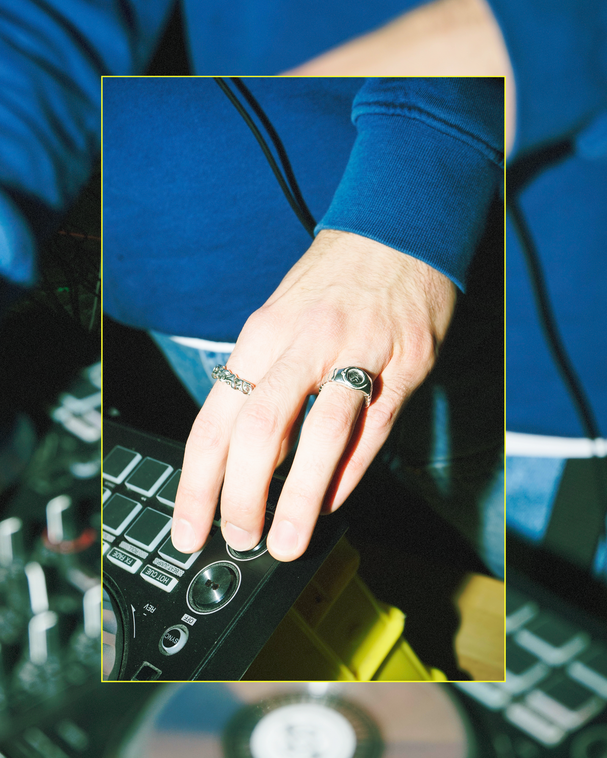 11:11 silver watch ring worn on a hand over DJ equipment