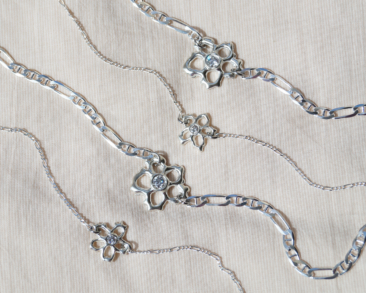 Close-up of layered sterling silver flower necklaces