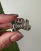 Engraved sterling silver pet tag with gemstone detail, shown on neutral linen background