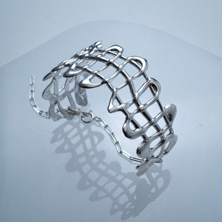 Sterling silver organic cage-style bracelet that can be worn as everyday wearable art on a light gray background