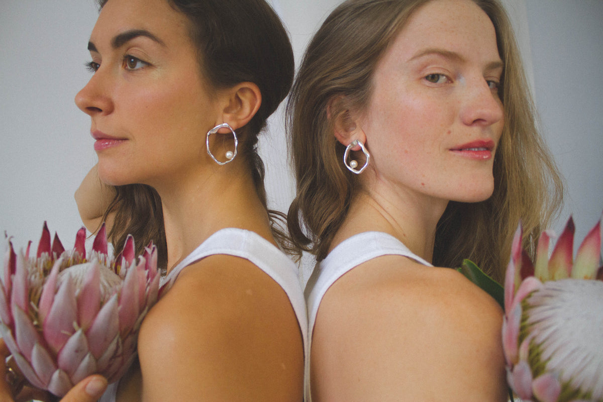 Close-up of Mother sculptural earrings worn on the ear