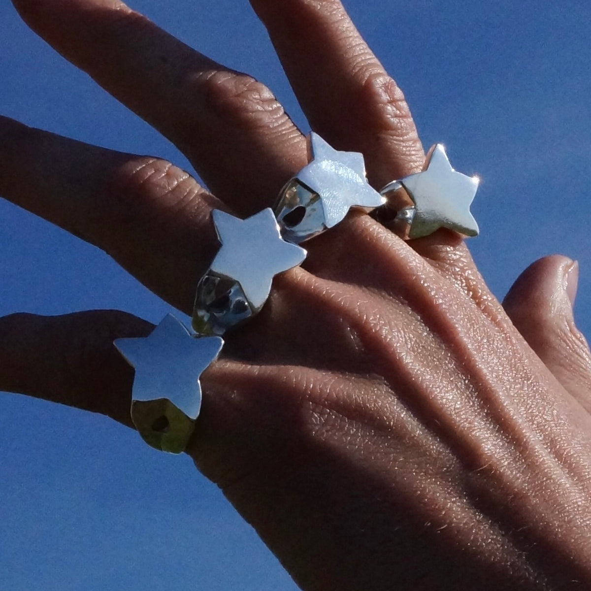 Four sterling silver Star Signet rings styled on a hand