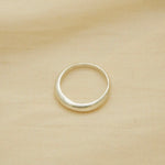 thin yet sturdy silver ring, bulbous and smooth, sitting on fabric