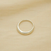 thin yet sturdy silver ring, bulbous and smooth, sitting on fabric