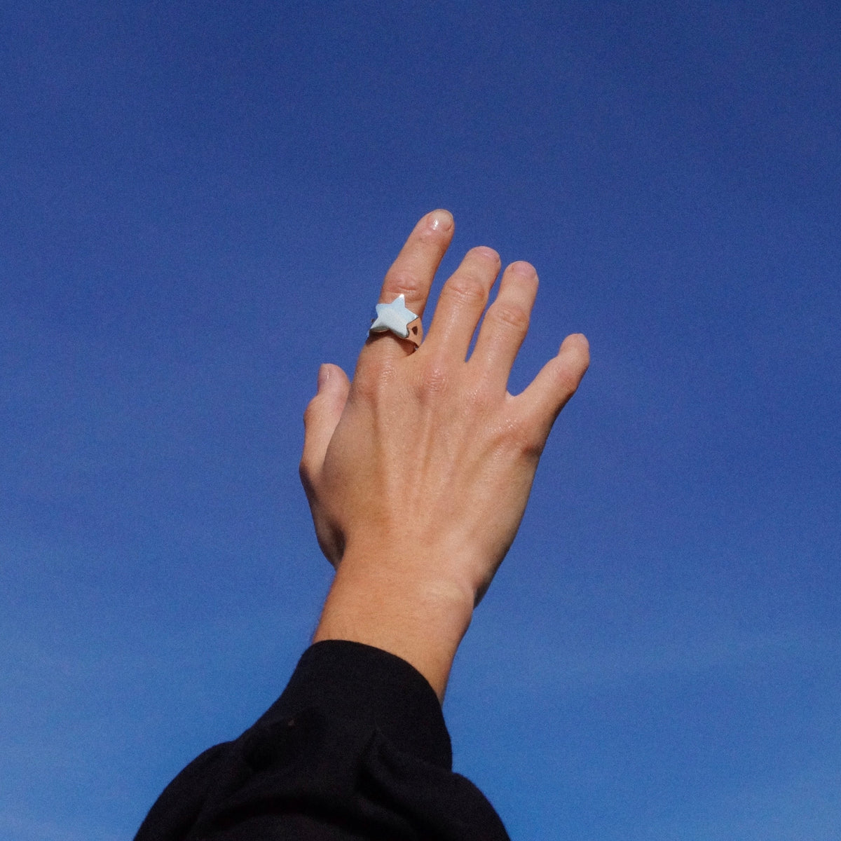 Star Signet ring worn on a hand against a blue sky